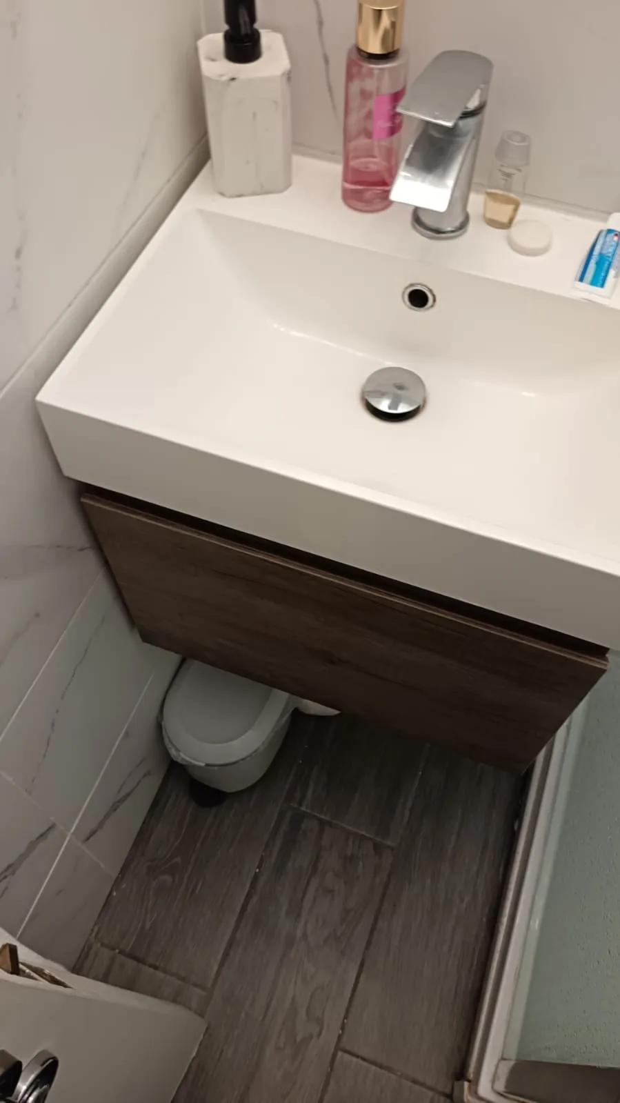 Engineer checking a bathroom basin waste for signs of a blockage before quoting drain unblocking cost