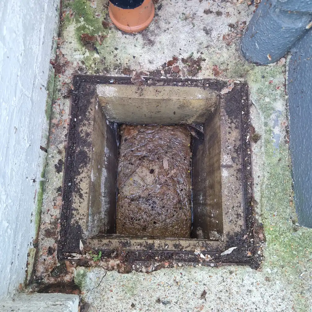 Sewage backed up to the top of a blocked inspection chamber during drain unblocking in Crawley