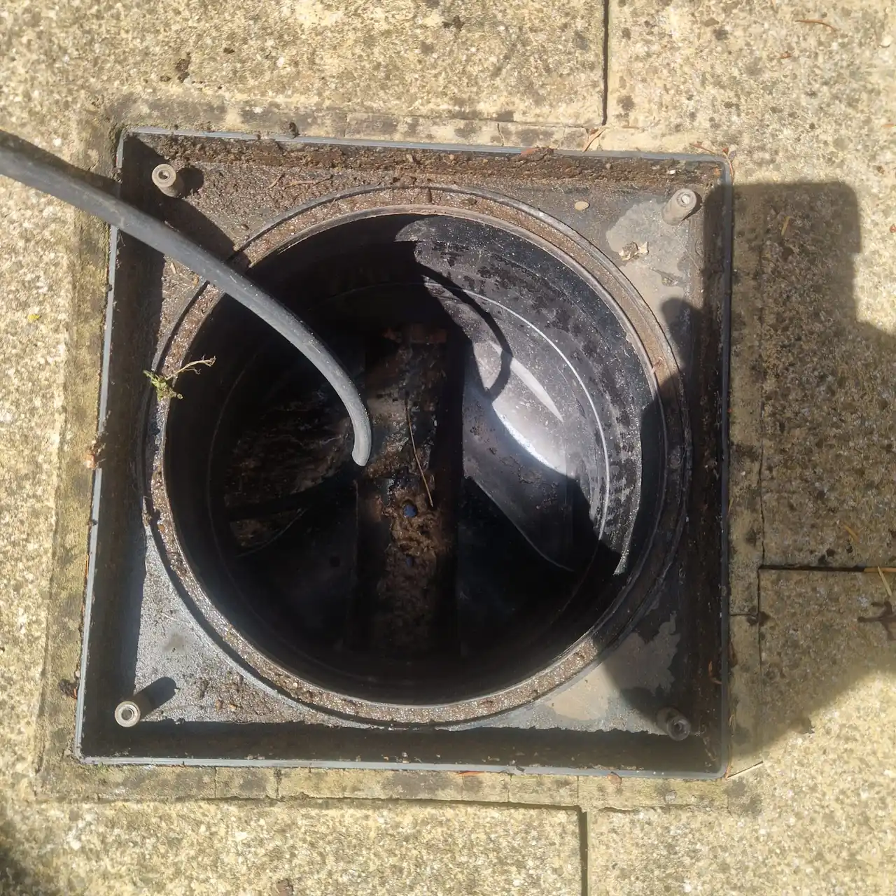 Engineer feeding a CCTV drain camera into a manhole with a monitor showing pipe interior during a cctv drain survey cost inspection
