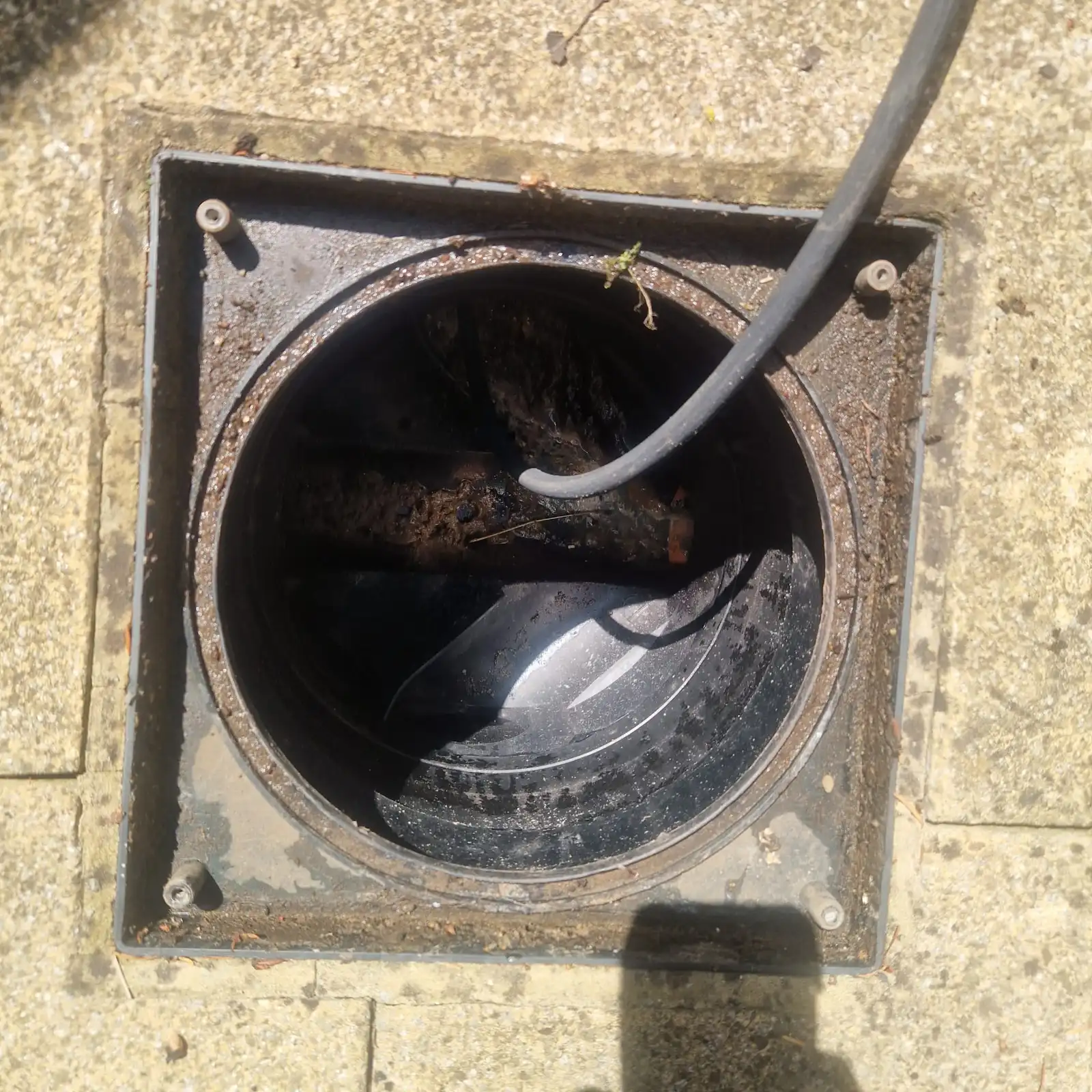 Engineer running CCTV drain survey cable into plastic inspection chamber on blocked drains Tunbridge Wells job