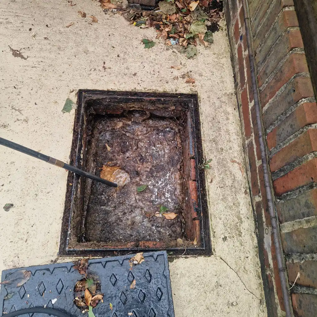 Drainage engineer using high pressure jetting equipment on a blocked chamber