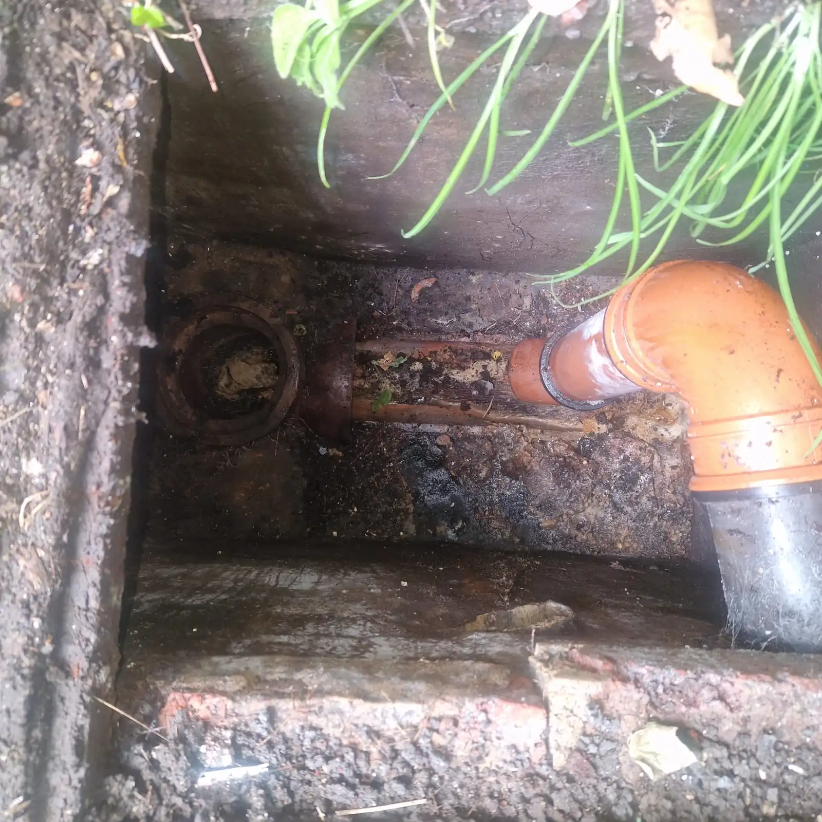 Set of connected drainage rods being fed into an inspection chamber - how to use drain rods