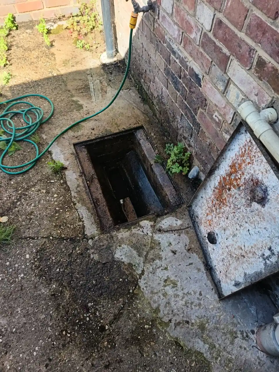 engineer removing a U-bend trap under a sink to clear a blockage into a bucket