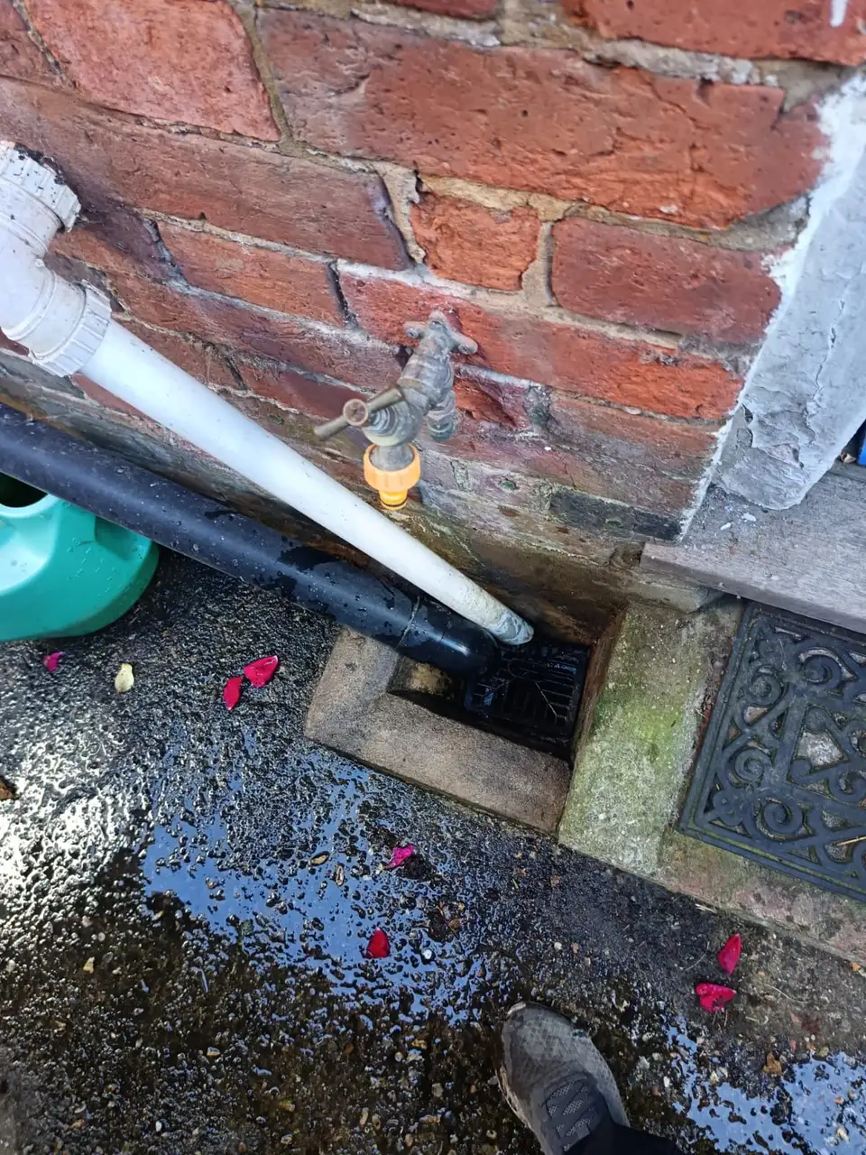 Outside gully grate lifted to inspect a blocked drain before clearance