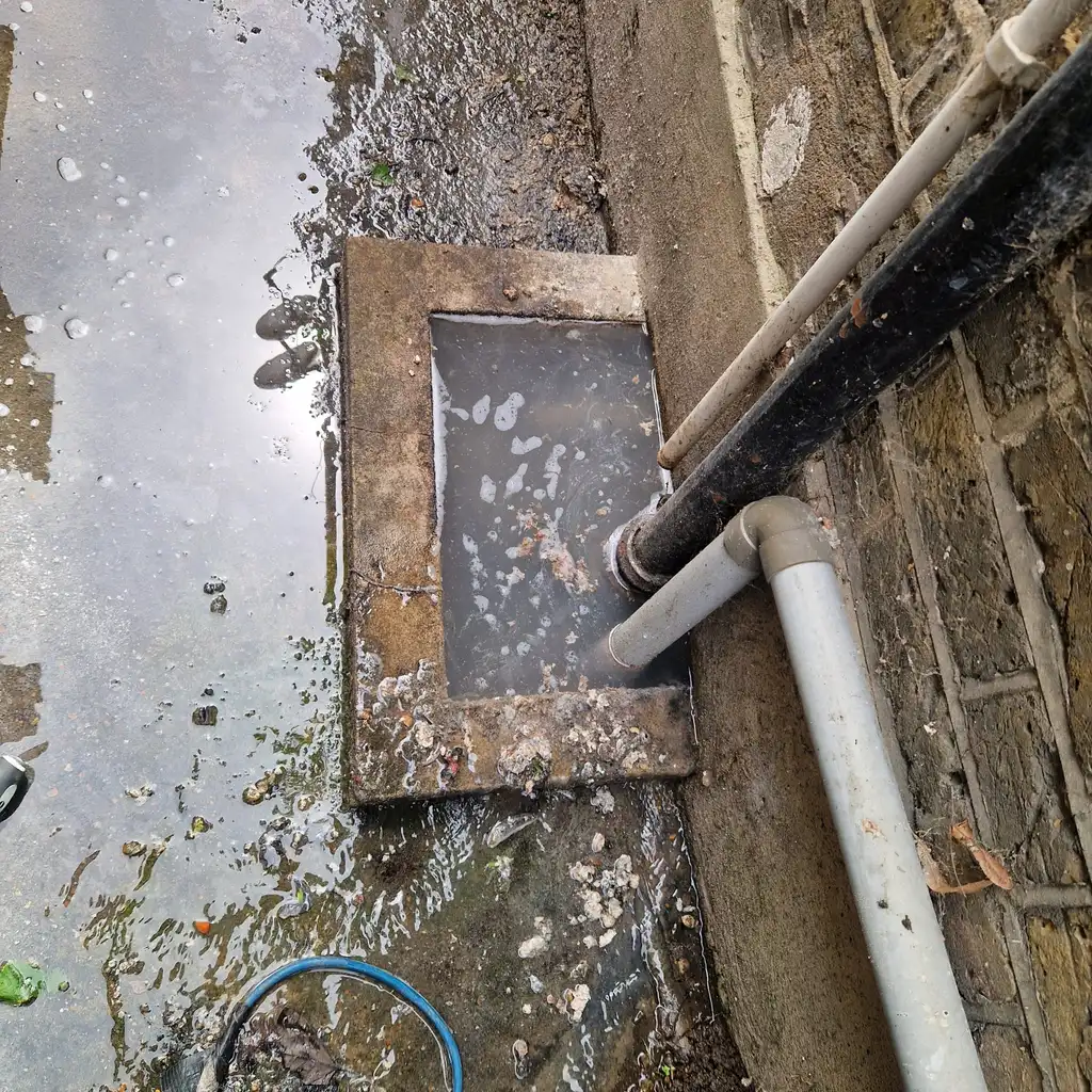 Overflowing blocked gully outside a UK property before a drainage camera inspection