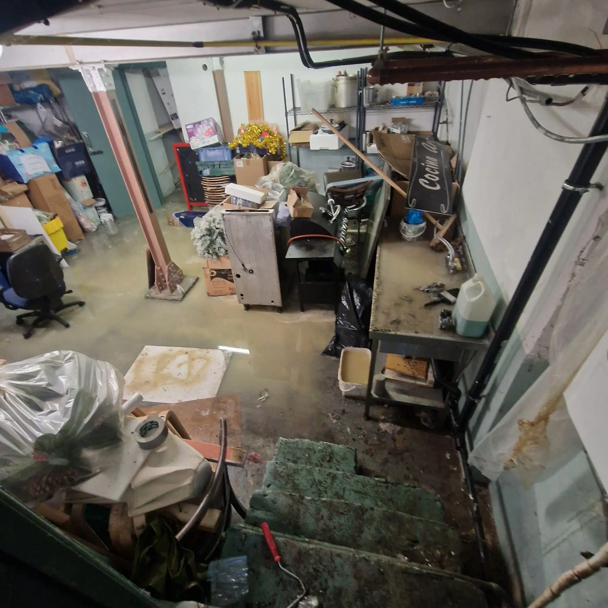 Standing waste water covering a basement floor before pumping and cleanup in South West London